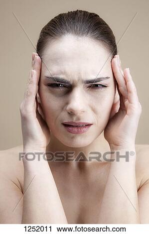 A grimacing young woman with her hands to her temples View Large Photo Image Stock Image - A grimacing young woman with her hands to her temples . Fotosearch