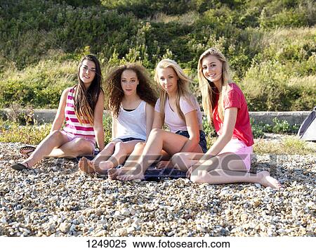 A group of four friends sitting in the sun on a rocky beach View Large Photo Image Stock Photography - A group of four friends sitting in the sun on a rocky beach. Fotosearch