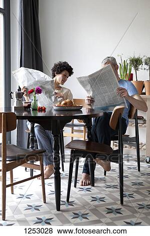 A hip mixed aged couple reading newspapers and having breakfast View Large Photo Image Stock Photo - A hip mixed aged couple reading newspapers and having breakfast. Fotosearch