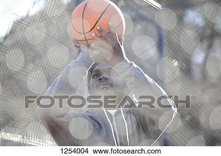 A hip young man aiming a basketball while on an outdoor basketball court View Large Photo Image Picture - A hip young man aiming a basketball while on an outdoor basketball court. Fotosearch