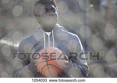 A hip young man looking away thoughtfully while holding a basketball View Large Photo Image Stock Image - A hip young man looking away thoughtfully while holding a basketball. Fotosearch