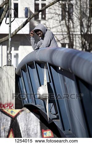 A hip young man standing on a bridge and looking down View Large Photo Image Stock Photography - A hip young man standing on a bridge and looking down . Fotosearch