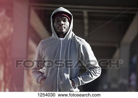 Stock Image - A hip young man standing under a city bridge in sports gear. Fotosearch