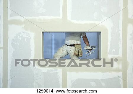 A house painter holding a trowel, seen through window hole in a newly constructed wall View Large Photo Image Picture - A house painter holding a trowel, seen through window hole in a newly constructed wall. Fotosearch