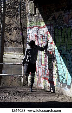 A man stretching while leaning against a graffiti strewn wall View Large Photo Image Stock Photo - A man stretching while leaning against a graffiti strewn wall. Fotosearch