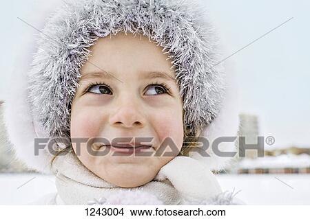 A mischievously smiling young girl wearing a fur hat outdoors in winter View Large Photo Image Picture - A mischievously smiling young girl wearing a fur hat outdoors in winter. Fotosearch