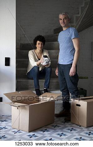Stock Image - A mixed age couple packing moving boxes. Fotosearch