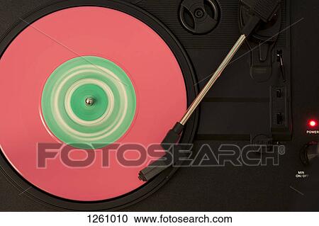 Stock Image - A pink and green vinyl record playing on a turntable. Fotosearch