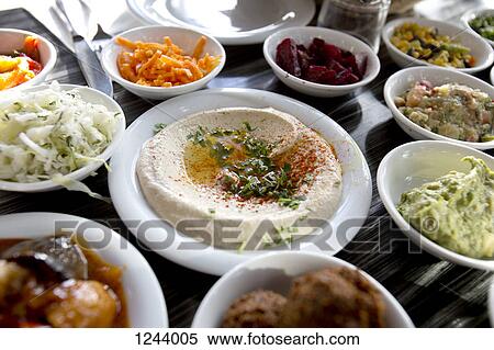 A plate of garnished hummus on table surrounded by various salads View Large Photo Image Stock Photography - A plate of garnished hummus on table surrounded by various salads. Fotosearch