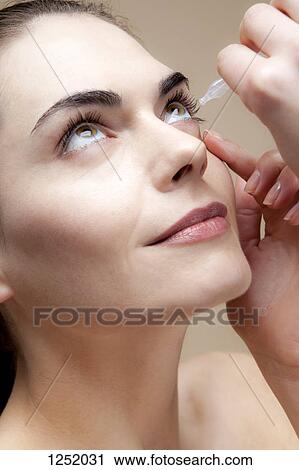A serenely smiling young woman applying eye drops to her eyes View Large Photo Image Stock Image - A serenely smiling young woman applying eye drops to her eyes. Fotosearch