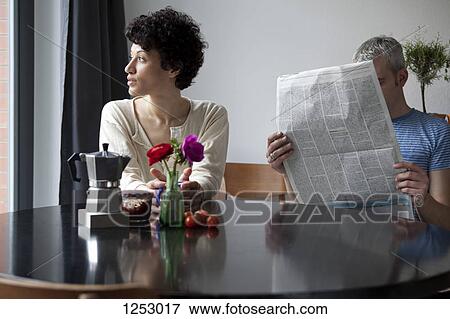 A serious woman looking out a window while her boyfriend hides behind a newspaper View Large Photo Image Stock Photo - A serious woman looking out a window while her boyfriend hides behind a newspaper. Fotosearch