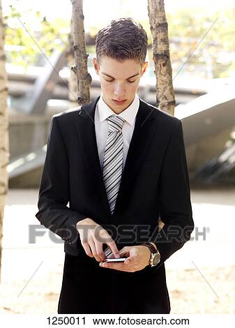 A serious young businessman text messaging on his smart phone View Large Photo Image Stock Image - A serious young businessman text messaging on his smart phone. Fotosearch