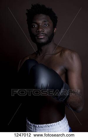 A serious young man posing in boxing shorts and boxing gloves View Large Photo Image Stock Image - A serious young man posing in boxing shorts and boxing gloves. Fotosearch