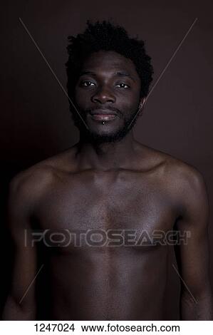 A shirtless hip young man standing against a brown background, waist up View Large Photo Image Picture - A shirtless hip young man standing against a brown background, waist up. Fotosearch