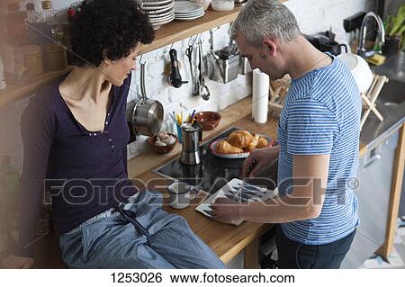 A smiling mixed age couple preparing food in their kitchen View Large Photo Image Stock Photograph - A smiling mixed age couple preparing food in their kitchen. Fotosearch