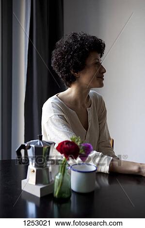 A smiling woman looking away while sitting at a table View Large Photo Image Stock Image - A smiling woman looking away while sitting at a table . Fotosearch