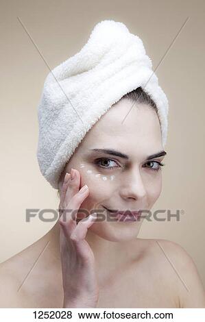 A smiling young woman applying moisturizer under her eye View Large Photo Image Stock Photo - A smiling young woman applying moisturizer under her eye. Fotosearch