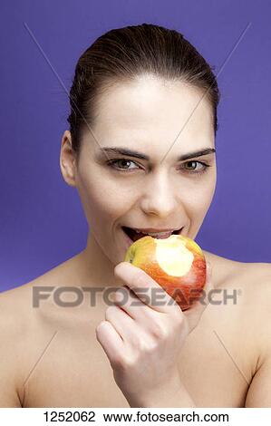 A smiling young woman eating in apple View Large Photo Image Stock Image - A smiling young woman eating in apple. Fotosearch