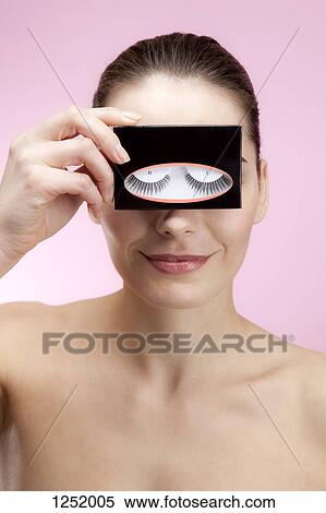 A smiling young woman holding a box of false eyelashes up to her eyes View Large Photo Image Stock Photography - A smiling young woman holding a box of false eyelashes up to her eyes. Fotosearch