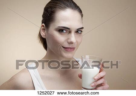 Stock Photo - A smiling young woman holding a glass of milk. Fotosearch