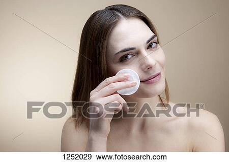 A smiling young woman using a cotton pad to clean her skin View Large Photo Image Stock Photo - A smiling young woman using a cotton pad to clean her skin. Fotosearch