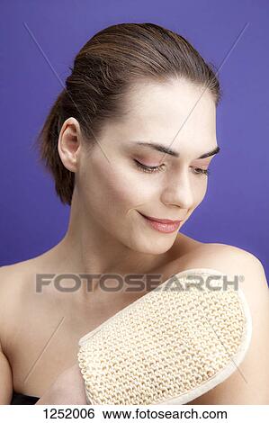 A smiling young woman using a loofah sponge View Large Photo Image Stock Photograph - A smiling young woman using a loofah sponge. Fotosearch