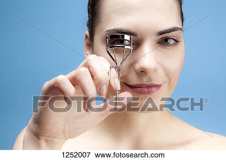 A smiling young woman using an eyelash curler on her eyelashes View Large Photo Image Stock Photo - A smiling young woman using an eyelash curler on her eyelashes. Fotosearch