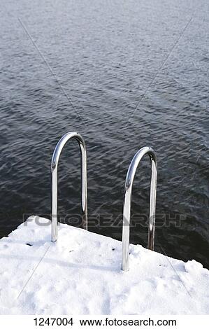 A snow covered dock with a ladder going into rippled water View Large Photo Image Picture - A snow covered dock with a ladder going into rippled water. Fotosearch