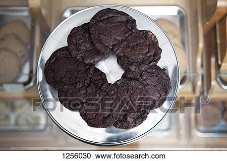 A tray of double chocolate chunk cookies on a tray on a display cabinet in a cafe View Large Photo Image Stock Image - A tray of double chocolate chunk cookies on a tray on a display cabinet in a cafe. Fotosearch