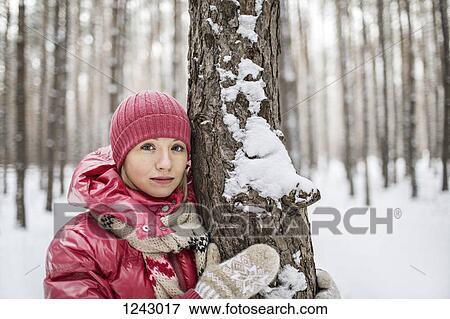 A woman wearing warm clothing posing next to a tree in winter View Large Photo Image Stock Photo - A woman wearing warm clothing posing next to a tree in winter. Fotosearch