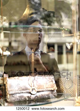 A young businessman adjusting his tie using a shop window as a mirror View Large Photo Image Stock Image - A young businessman adjusting his tie using a shop window as a mirror. Fotosearch