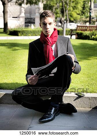 A young businessman holding a newspaper while sitting in a park View Large Photo Image Stock Photograph - A young businessman holding a newspaper while sitting in a park. Fotosearch