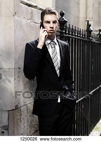 A young businessman looking serious while listening to his smart phone View Large Photo Image Stock Photograph - A young businessman looking serious while listening to his smart phone. Fotosearch