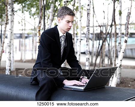 Stock Photography - A young businessman using a laptop at a city park. Fotosearch