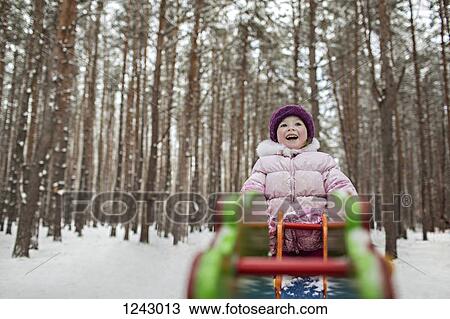 Stock Image - A young cheerful girl on a piece of playground equipment in winter. Fotosearch