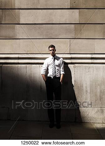 A young handsome businessman leaning against a building View Large Photo Image Stock Image - A young handsome businessman leaning against a building. Fotosearch