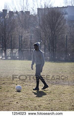 A young man kicking a soccer ball in a city park View Large Photo Image Stock Image - A young man kicking a soccer ball in a city park. Fotosearch