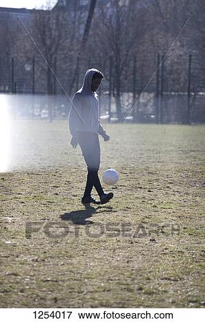 A young man kicking a soccer ball in a city park View Large Photo Image Stock Photo - A young man kicking a soccer ball in a city park. Fotosearch