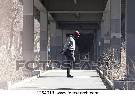 A young man stretching on a sidewalk under a city bridge View Large Photo Image Stock Photo - A young man stretching on a sidewalk under a city bridge. Fotosearch