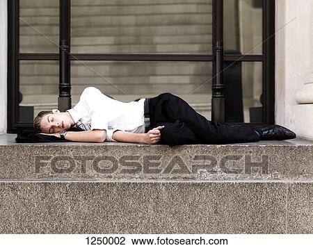 A young sleeping businessman lying on steps outside a building View Large Photo Image Stock Image - A young sleeping businessman lying on steps outside a building . Fotosearch