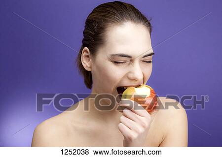 A young woman biting into an apple greedily View Large Photo Image Stock Photo - A young woman biting into an apple greedily. Fotosearch