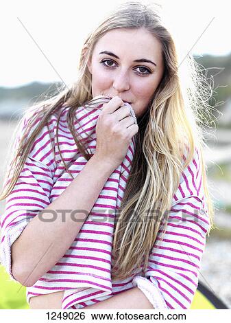 A young woman covering her mouth with her shirt and smiling playfully View Large Photo Image Stock Photograph - A young woman covering her mouth with her shirt and smiling playfully. Fotosearch