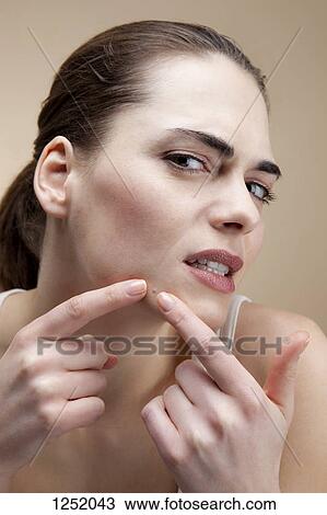 A young woman frowning in concentration as she squeezes a pimple View Large Photo Image Stock Image - A young woman frowning in concentration as she squeezes a pimple. Fotosearch