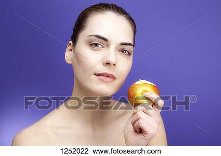 Stock Image - A young woman holding an apple she's been eating. Fotosearch