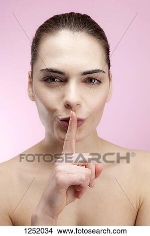 A young woman putting her finger to her lips playfully View Large Photo Image Picture - A young woman putting her finger to her lips playfully. Fotosearch