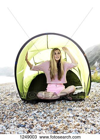 A young woman sitting in a beach tent on a rocky beach View Large Photo Image Stock Image - A young woman sitting in a beach tent on a rocky beach. Fotosearch