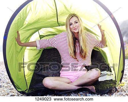 A young woman sitting in a beach tent on a rocky beach View Large Photo Image Stock Image - A young woman sitting in a beach tent on a rocky beach. Fotosearch