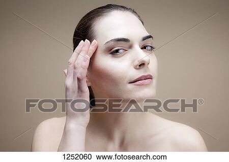 Stock Image - A young woman touching her temple. Fotosearch