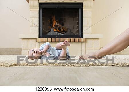 Baby and mother's leg on carpet in front of fire View Large Photo Image Stock Photography - Baby and mother's leg on carpet in front of fire. Fotosearch