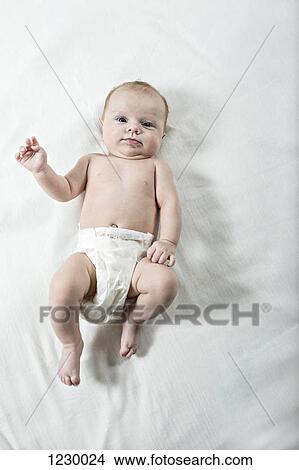 Picture - Baby laying on bed and looking at camera. Fotosearch